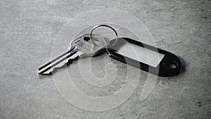 Metallic Key with Black Plastic Key Tag on Gray Surface