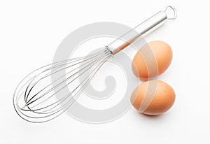Metallic kitchen rods for manually mixing food with 2 fresh eggs collection of cooking objects. Isolated.