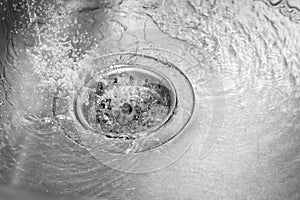 Metallic kitchen sink drain swirly water flow