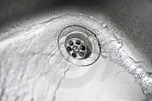 Metallic Kitchen sink swirly water flow and drops