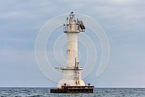 Metallic lighthouse with cormorant birds on top in Tsemes Bay of Black Sea by Novorossiysk