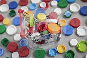 Metallic mini trolley with colored plastic caps. Concept of recycling plastic