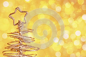 Metallic modern christmas tree on golden tint light bokeh background, xmas holiday