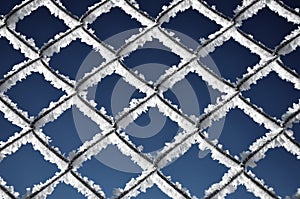 Metallic net covered with hoarfrost. Extreme cold weather concept