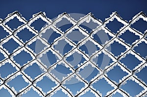 Metallic net covered with hoarfrost. Extreme cold weather concept