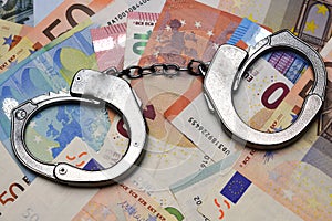 Metallic police handcuffs on euro banknotes suggesting corruption or criminal delinquency photo