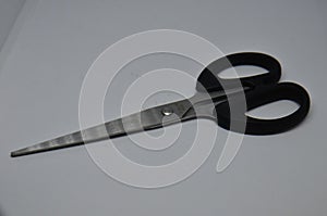 Metallic scissors with black holder on white background