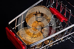 Metallic shiny bitcoin cryptocurrency coin with Ukrainian hryvnia coins in grocery shopping cart. Electronic decentralized money