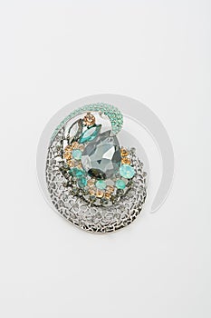 Metallic silver brooch with green gemstones imitation, pin on white background, bijouterie, jewelry close up