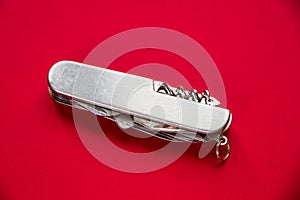 Metallic swiss knife isolated on red