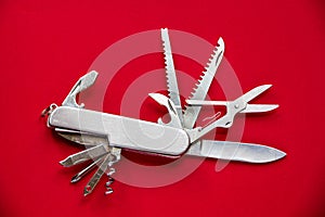 Metallic swiss knife isolated on red