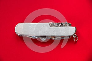 Metallic swiss knife isolated on red