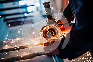 Metalworker cutting iron and metal with a electric rotary angle grinder and working, generating metal sparks photo