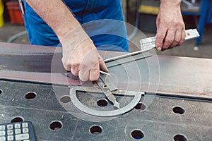 Metalworker using folding rule to measure steel strip photo