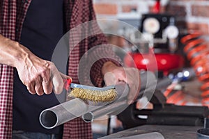 Metalworker using a hand metal brush