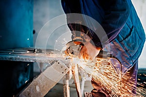 Metalworker using small electrical grinder and cutting metal