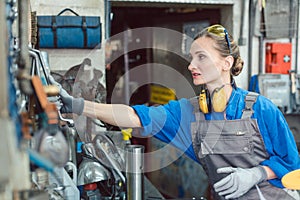 Metalworker woman in workshop grabbing tool photo