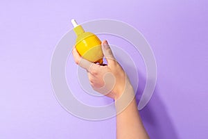 Metaphor, bottle serum with vitamin C for skin in lemon in female hand. The concept vegetable cosmetics and aromatherapy