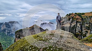 Meteora - Man with scenic view of steep rock formations. Holy Monastery of Varlaam on cloudy moody day in Kalambaka, Meteora