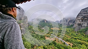 Meteora - Selected focus on man with panoramic view of Holy Orthodox Monastery of Rousanou, Meteora