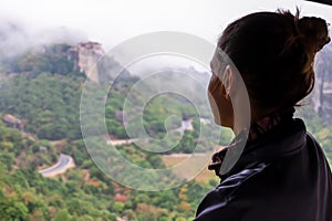 Meteora - Selected focus on woman with panoramic view of Holy Orthodox Monastery of Rousanou, Meteora