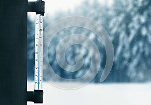 Meteorology, forecasting and winter weather season concept - thermometer on a glass window with snowy winter forest background