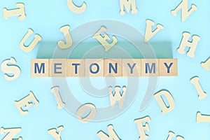 Metonymy figure of speech concept in English grammar class lesson. Wooden blocks typography flat lay in blue photo