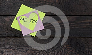 Metoo message written on pink heart paper on wooden background