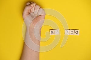 MeToo on wooden alphabet, used for concept of sexual harrassment. Woman fist as protest in shot