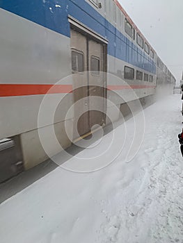 Metra train pulls into station during snowstorm with blowing snowdrifts