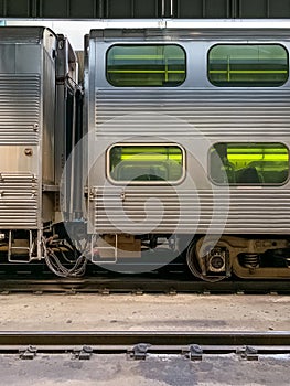 Metra train on railroad tracks in terminal of train station in Chicago, with view through window of passenger taking a seat