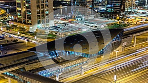 Metro station near Buildings of Jumeirah Lakes Towers with traffic on the road night timelapse.