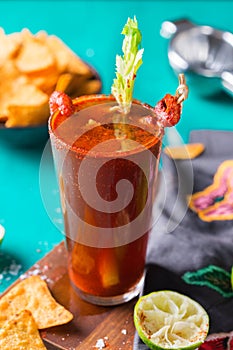 Mexican alcohol cocktail Clamato beer with shrimps and celery stick photo