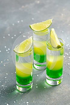 Mexican alcoholic cocktail drinks shot. made of Absinthe, Lemon Fresh, Grenadine. green alcoholic cocktail with lime