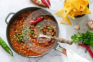 Mexican and American food Chili con carne served with nachos, pepper and herbs.