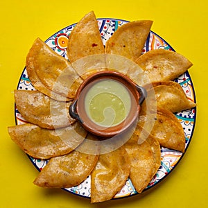 Mexican basket tacos also called canasta with  green sauce on yellow background