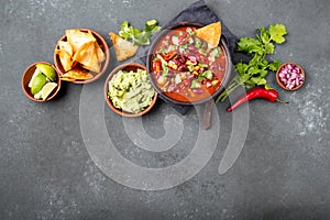 Mexican black bean soup with tomato, avocado and totopos. Gray background, top view