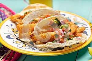 Mexican breaded fish tacos also called ensenada on turquoise background