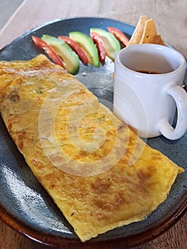 Mexican breakfast of egg omelette stuffed with mushrooms accompanied by avocado, tomato, red sauce, beans with cheese and tortilla