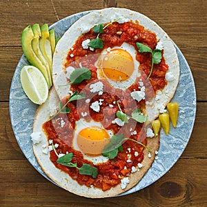 Mexican breakfast huevos rancheros: fried egg with salsa closeup in the pan