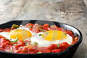 Mexican breakfast: Huevos rancheros in iron frying pan on wood