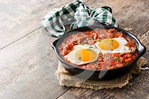 Mexican breakfast: Huevos rancheros in iron frying pan on wood