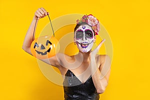 Mexican Catrina, portrait of young latin woman holding a plastic calaverita pumpkin for Halloween party in Mexico photo