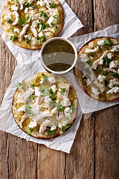 Mexican Chalupas with cheese and chicken meat and sauce salsa verde closeup Vertical top view