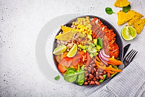 Mexican chicken burrito bowl with rice, beans, tomato, avocado,corn and spinach, top view. Mexican cuisine food concept