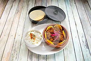 Mexican cochinita pibil stew accompanied by white rice with pico de gallo and corn tortillas