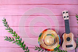 Mexican composition with copy space. Guitar and sombrero hat on pink background.