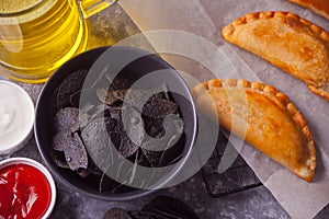 Mexican corn chips nachos and fried meat pies empanadas cheburek with dips. Black chips nachos for brutal men. Top view
