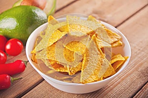 Mexican corn chips nachos with vegetables on the wooden table