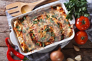 Mexican enchilada in a baking dish horizontal top view close-up photo